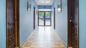 Un couloir aux murs bleus, aux portes en bois et au sol à carreaux.