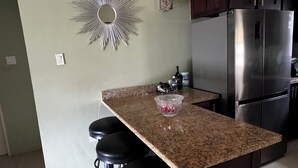 Eine Küche mit Granit Arbeitsplatte, Edelstahl-Kühlschrank und dunklen Holzschränken.