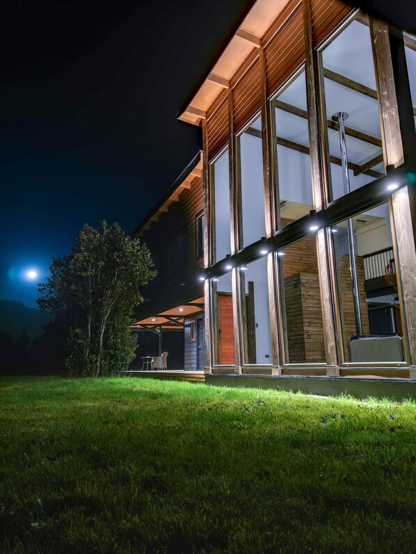 A modern house with large glass windows and wooden exterior. - Entre Volcanes Lodge (Puerto Varas)