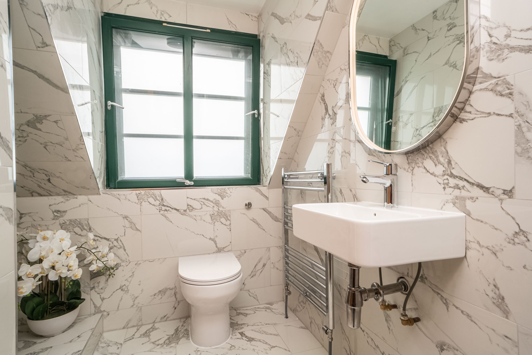 Une salle de bain avec des toilettes, un lavabo, un miroir et une fenêtre.