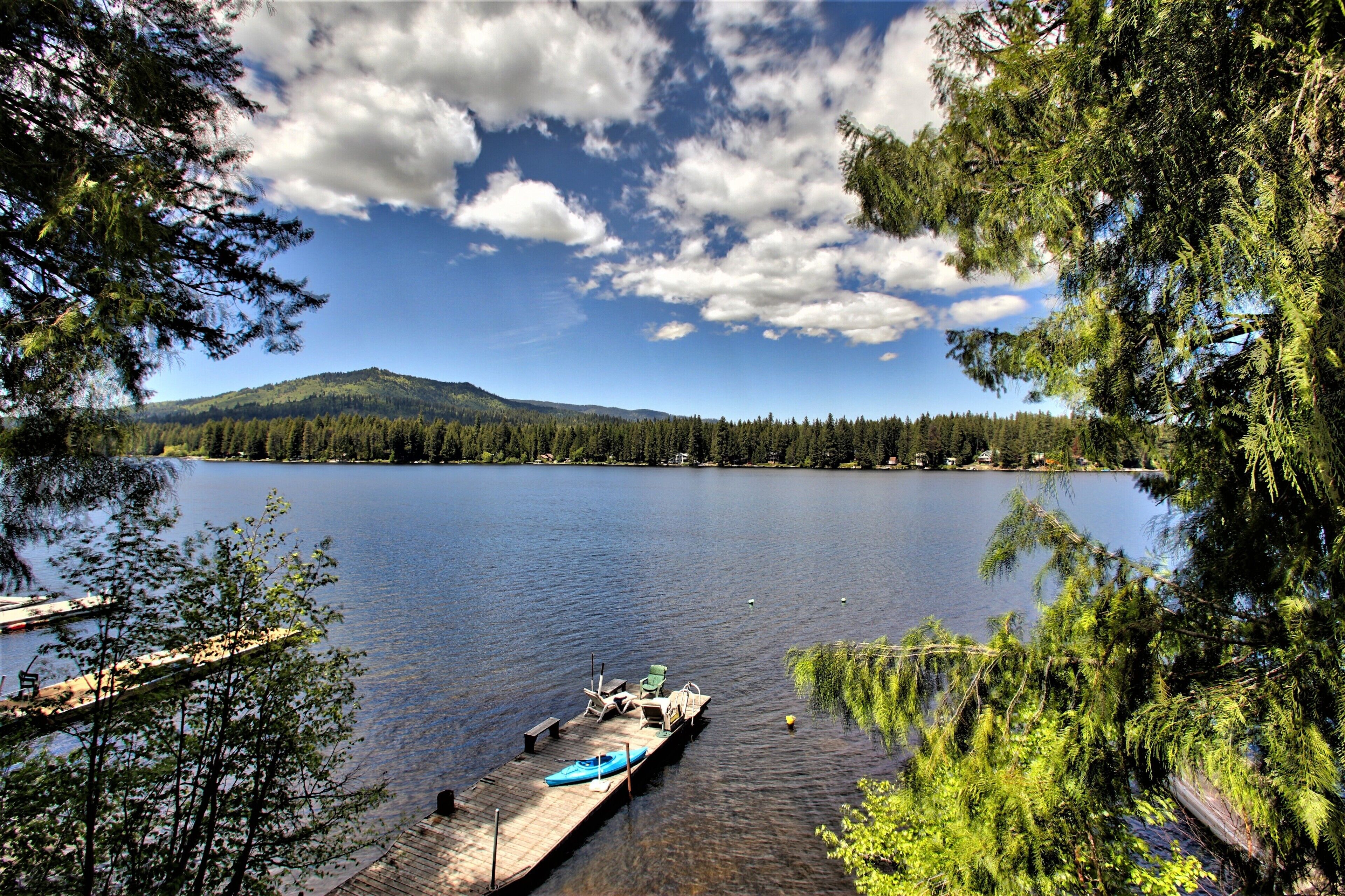 A lake with a dock, boats, and a mountain in the background.