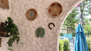 Un mur à texture orné d’assiettes décoratives et d’une plante suspendue.