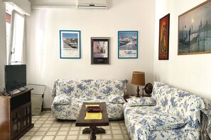 Ein Wohnzimmer mit einer Couch, einem Couchtisch, einem Fernseher und gerahmten Bildern an der Wand.