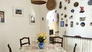 Un coin repas avec une table dressée pour quatre personnes, un vase rempli de fleurs jaunes et diverses décorations murales.