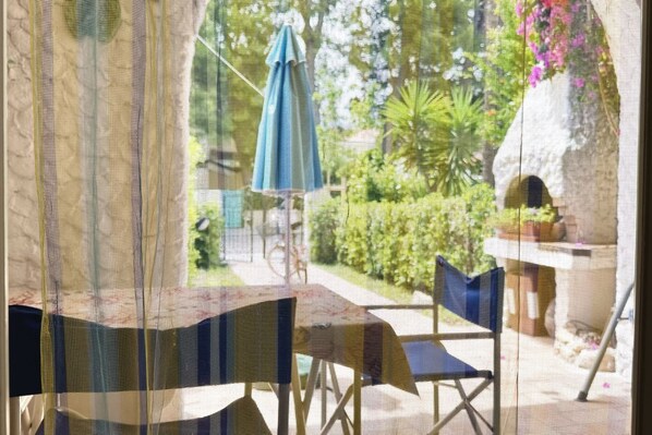 A patio with a table and chairs, a blue umbrella, and a stone structure.