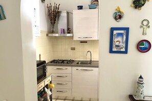 A kitchen with white cabinets, a gas stove, a microwave, and a sink.