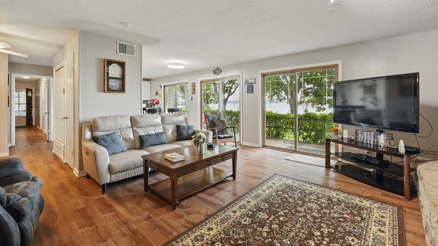 A spacious living room with a sofa, coffee table, and a TV on a stand. - EZ Access Lake House (Quinlan)