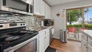 A modern kitchen with stainless steel appliances, white cabinets, and a view to the outside. - EZ Access Lake House (Quinlan)