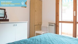 Un dormitorio con cama, armario, silla y radiador.