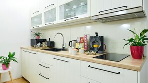 Una cucina moderna con mobili bianchi, un piano di lavoro nero e una cappa in acciaio inossidabile.