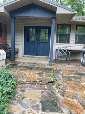 A house with a stone patio, a blue front door, and a covered porch area.