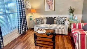 Ein Wohnzimmer mit einem gestreiften Sofa, einem Holztisch und einem Deckenventilator.
