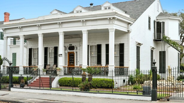 A white colonial-style building with a front porch, columns, and a staircase leading to the entrance. - Ashton's Bed and Breakfast (New Orleans)