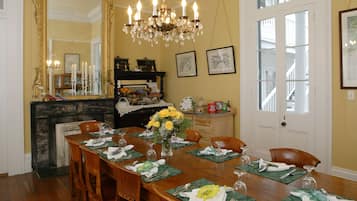 A dining room with a wooden table set for six, a chandelier, and a fireplace.