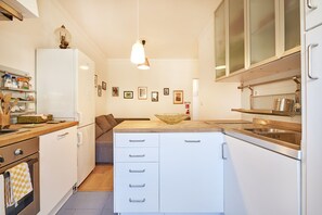 Cozinha moderna com armários brancos, bancada de madeira e luminária pendente.
