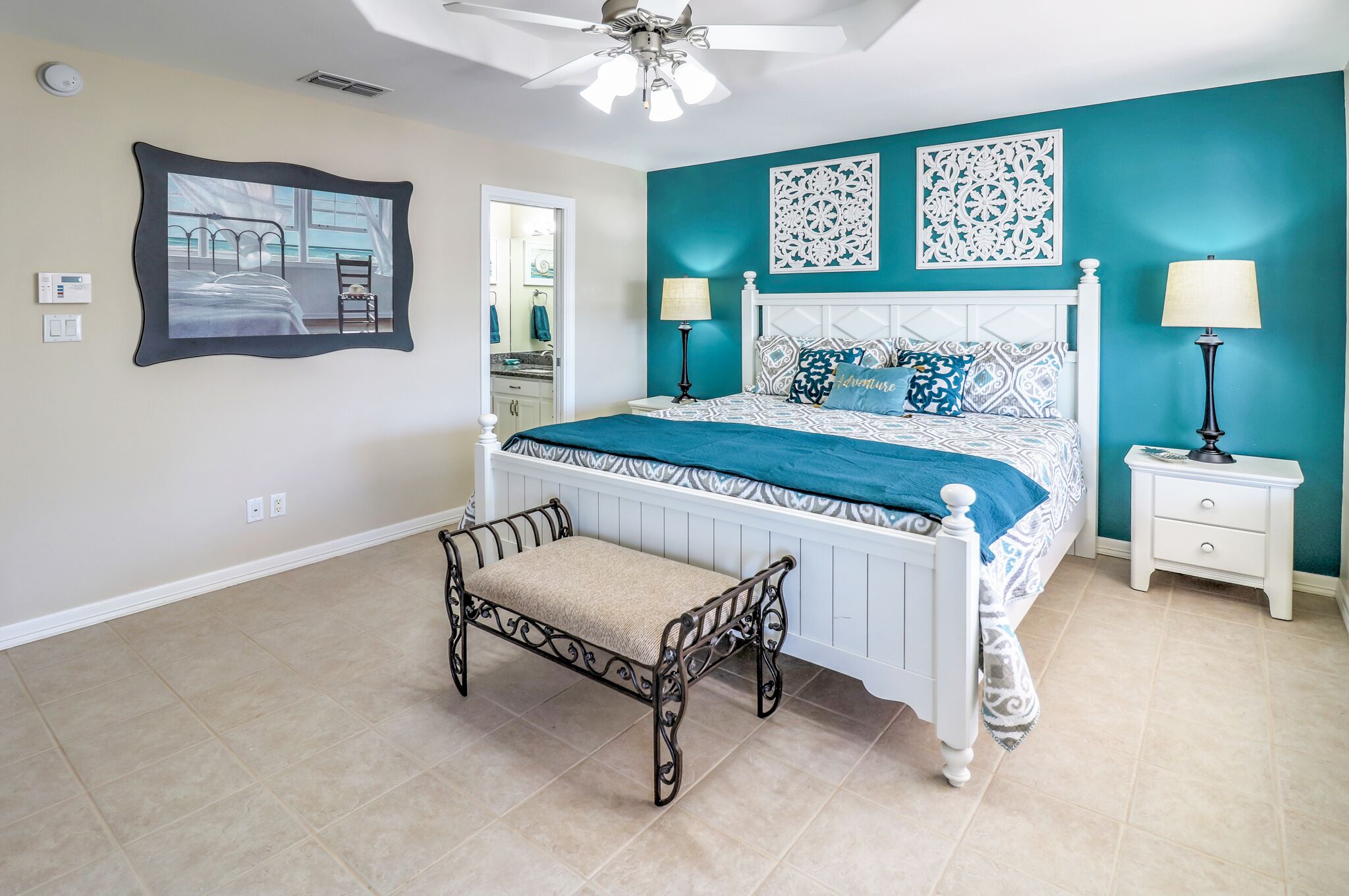 A bedroom with a bed, bedside tables, a bench, and decorative wall art.