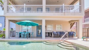 A two-story building with a pool, outdoor seating, and a balcony. - Southern Destination: Bask longer, save 10% on stays of 7+ nights! (South Padre Island)