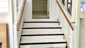 Eine Treppe führt zu einem Raum mit Blick auf eine Küche und eine Tür.