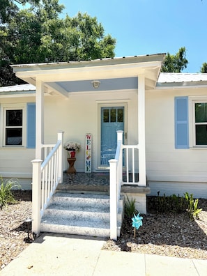 A house with a porch, a welcome sign, and a blue door.