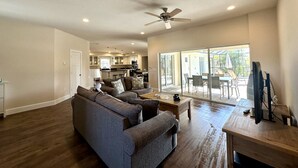 A spacious living room with a gray sofa, a wooden coffee table, and a TV stand. - * Where beach days, pool nights, and unforgettable memories begin! * (Englewood)
