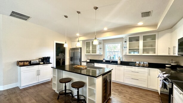 A modern kitchen with a central island, bar stools, stainless steel appliances, and white cabinetry. - * Where beach days, pool nights, and unforgettable memories begin! * (Englewood)