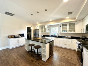 A modern kitchen with a central island, bar stools, stainless steel appliances, and white cabinetry. - * Where beach days, pool nights, and unforgettable memories begin! * (Englewood)