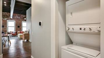 A laundry room with a white washing machine and dryer, a brick wall, and a wooden floor.