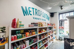 A variety store named 'METROPOLITAN VARIETY STORE' with shelves stocked with beverages, snacks, and other items.