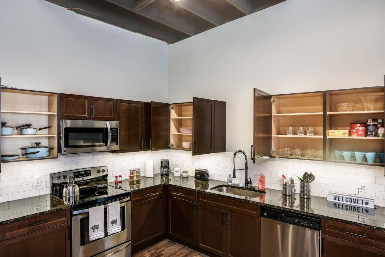 A modern kitchen with dark wood cabinets, stainless steel appliances, and a 'WELCOME!' sign.