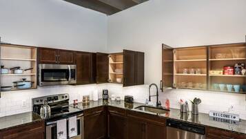 A modern kitchen with dark wood cabinets, stainless steel appliances, and a 'WELCOME!' sign.