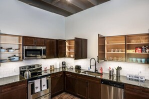 A modern kitchen with dark wood cabinets, stainless steel appliances, and a 'WELCOME!' sign. - Gorgeus One Of A Kind Loft Minutes From Downtown (Detroit)