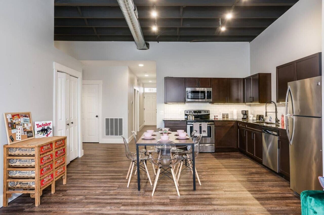 A modern kitchen with stainless steel appliances, wooden cabinets, and a dining area with a table set for four.