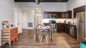 A modern kitchen with stainless steel appliances, wooden cabinets, and a dining area with a table set for four.