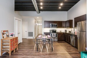 A modern kitchen with stainless steel appliances, wooden cabinets, and a dining area with a table set for four.
