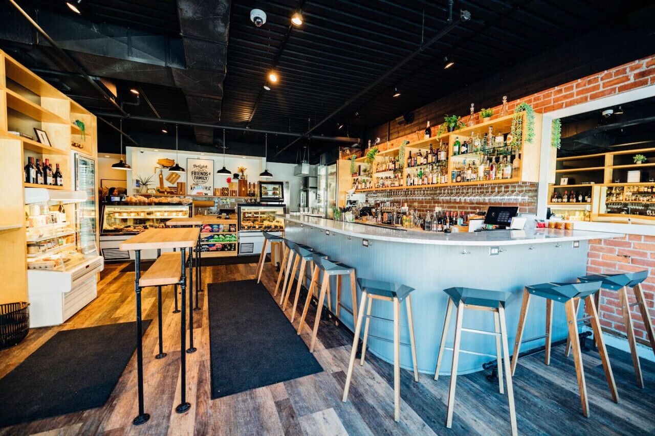 A bar area with stools, a counter, and shelves with bottles.