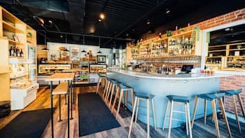 A bar area with stools, a counter, and shelves with bottles.