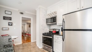 Una cocina moderna con armarios blancos, electrodomésticos de acero inoxidable y encimera de granito.