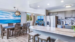 Een moderne keuken met een groot eiland, een houten eettafel en stoelen.