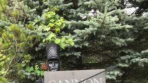 A sign for "Cannon Gates" amidst lush greenery and a statue.