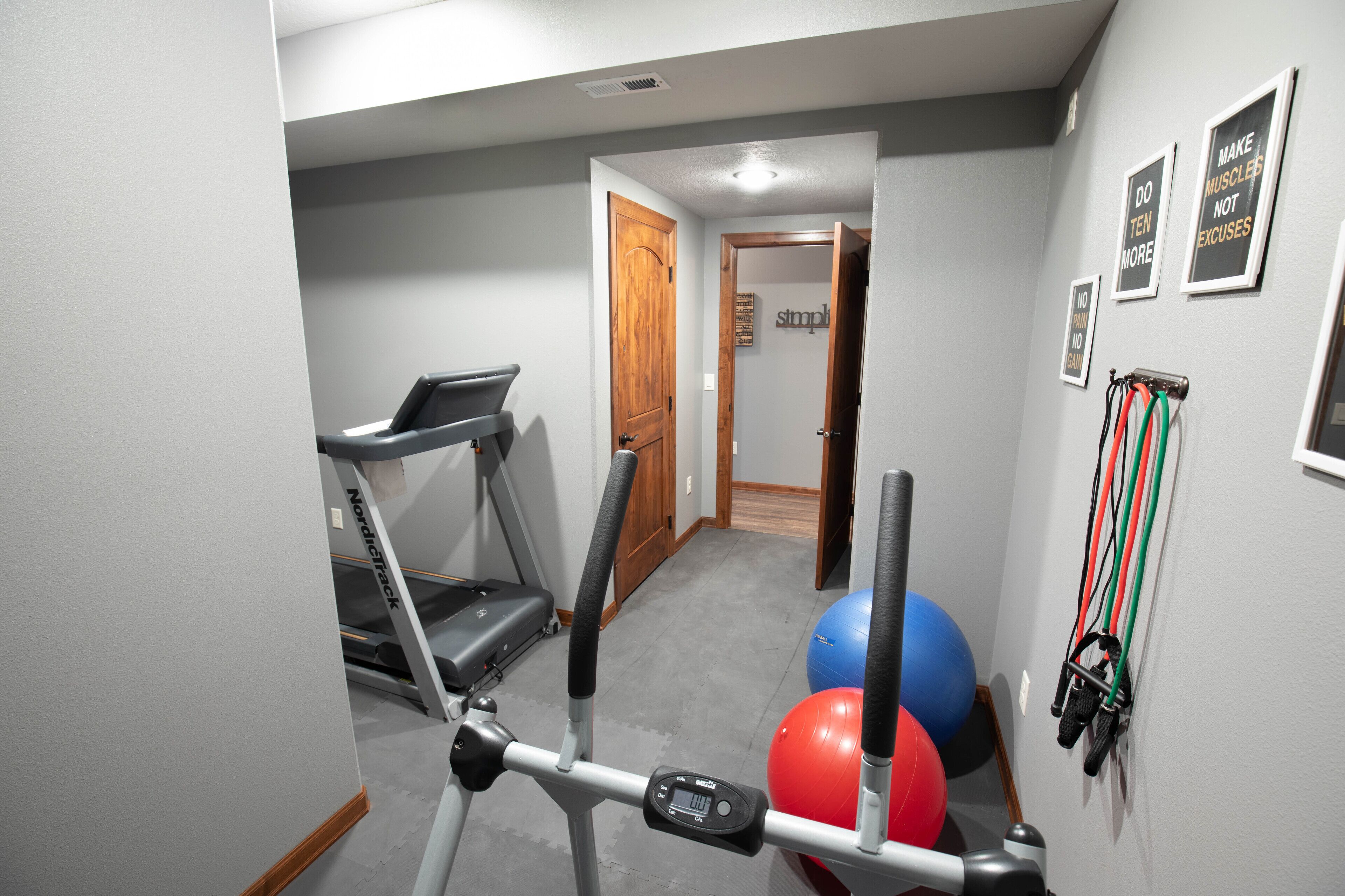 A home gym with exercise equipment, including a treadmill, stationary bike, and exercise balls.