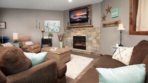 Una sala de estar con chimenea, asientos cómodos y televisor.