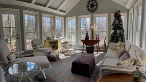 Un salon chaleureux avec une grande fenêtre, une cheminée et un sapin de Noël.