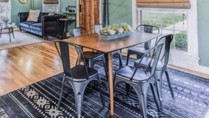 Un espace repas doté d’un plafond en bois, d’un lustre et d’une table dressée pour six personnes.
