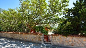 A stone wall with a metal gate, trees, and a clear sky. - Apartment Jelena by Interhome (Karlobag)