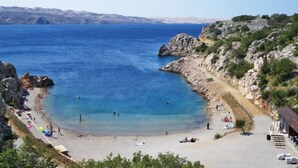 A coastal beach with clear blue waters, rocky cliffs, and a sandy shore. - Apartment Jelena by Interhome (Karlobag)