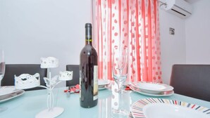 A dining table with a bottle, glasses, and plates. - Apartment Jelena by Interhome (Karlobag)