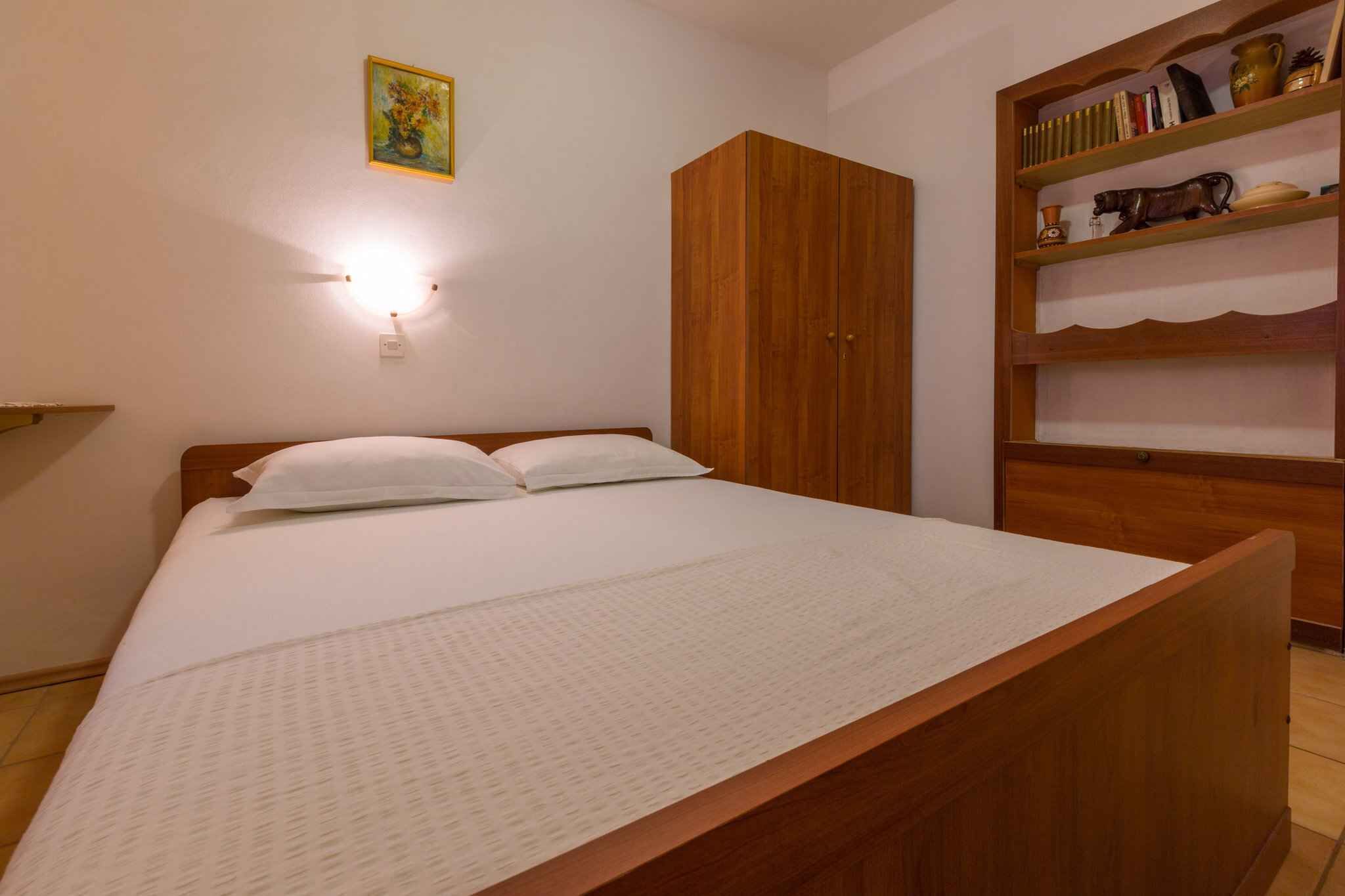 Una camera da letto con un letto di legno, un armadio e uno scaffale con libri e oggetti decorativi.