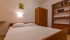 Una camera da letto con un letto di legno, un armadio e uno scaffale con libri e oggetti decorativi.