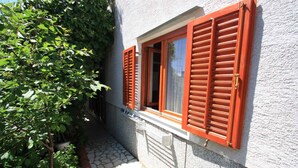 Un edificio con un vialetto in pietra che conduce a una finestra con persiane rosse.