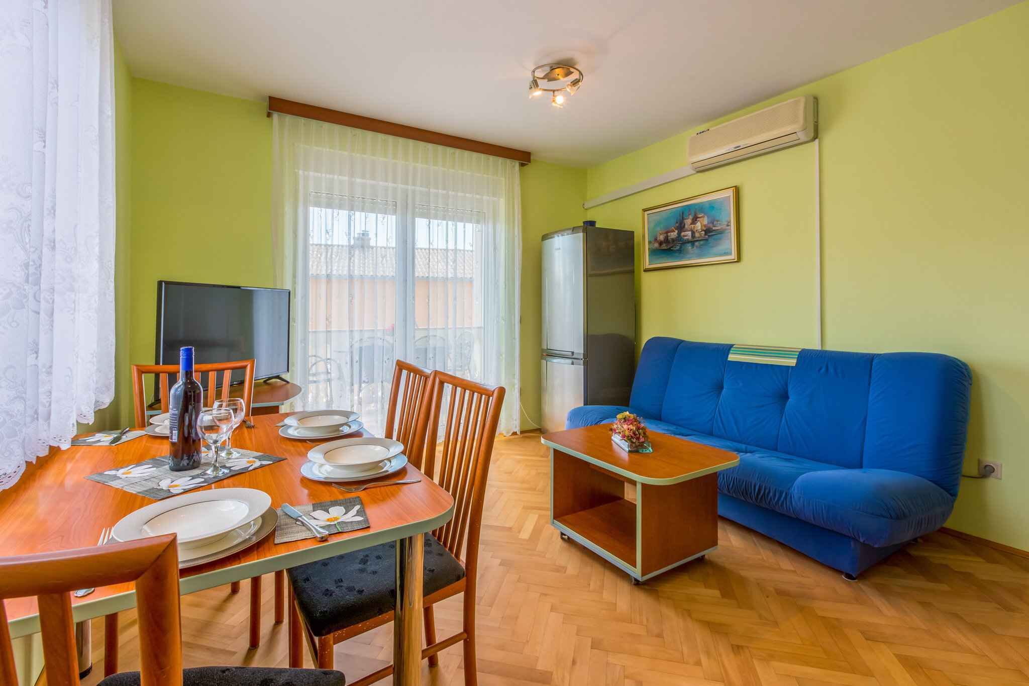 Un coin repas avec une table en bois dressée pour quatre personnes, un canapé bleu et un téléviseur.